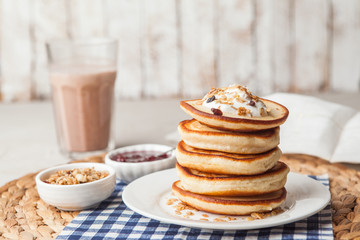 Pancakes stack on a white plate with cream and granola. Maslenitsa. Traditional Russian holiday. Shrove Tuesday, pancake day,