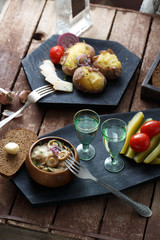 Pickled tomatoes, cucumbers, mushrooms and onion on wooden background with fork and shots of vodka.