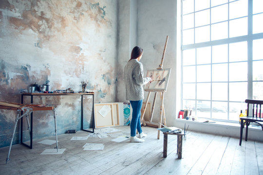 Young woman artist painting at home creative standing drawing