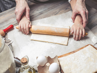 Mother and the daughter cook dough for home-made pastries. Happy family concept. Female and children's hands using rolling pins