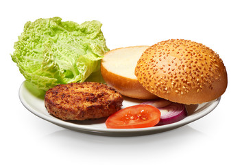 Hamburger, bun, onion, tomato,  and lettuce on white plate