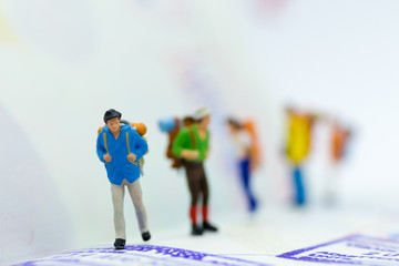 Miniature people : Backpacker group walking on passport. Image use for travel, business concept.