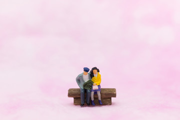 Miniature people: Couple sitting on the chair. Image use for Valentine's day concept.