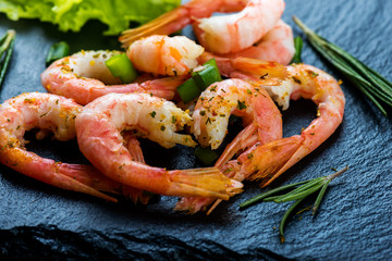 Cooked shrimps, prawns  with seasonings on dark stone background