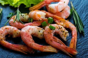 Cooked shrimps, prawns  with seasonings on dark stone background