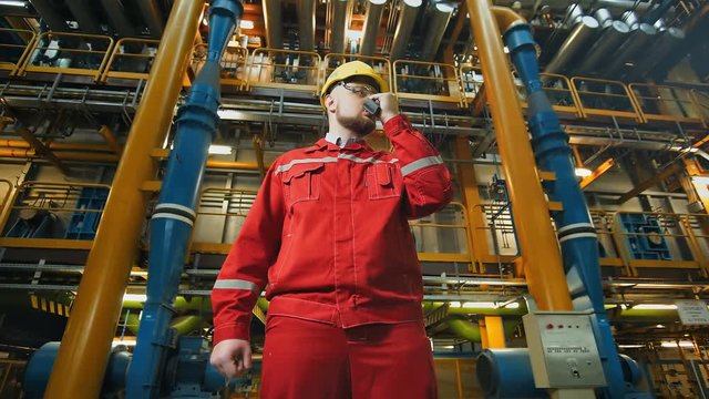 Industrial worker with walkie-talkie, controls work in a factory
