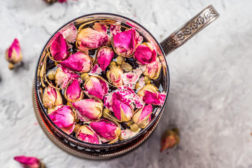Obraz na płótnie Canvas Vintage mug glass of tea with petals buds flowers dry pink rose