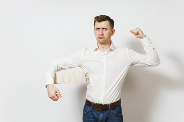 Young confused sad upset man in shirt holding wooden word Love isolated on white background. Copy...