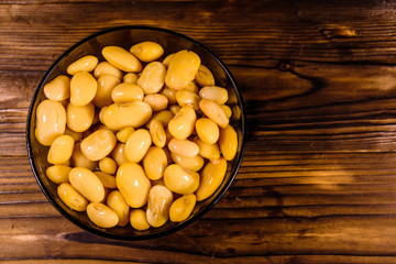 White marinated haricot beans in glass bowl on a wooden table. Top view