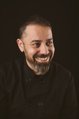 Portrait of a smiling chef looking to the rigth on a black background.