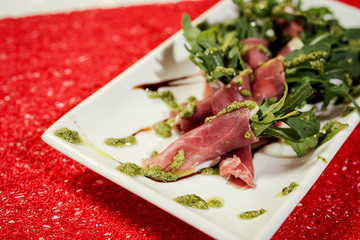 twisted bacon served with rucola and pesto sauce in restourant
