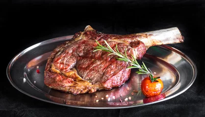 Photo sur Aluminium Steakhouse Single tomahawk rib steak on silver dish next to roasted cherry tomatoes