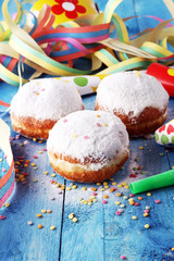 German donuts with jam and icing sugar. Carnival powdered sugar raised donuts with paper streamers.