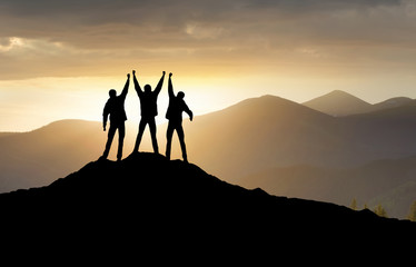 Silhouettes of team on mountain peak. Sport and active life concept.