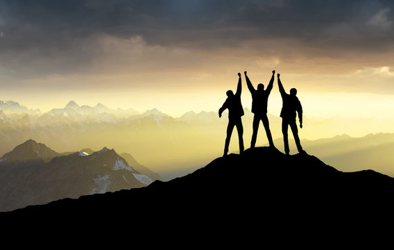 Silhouettes of team on mountain peak. Sport and active life concept.