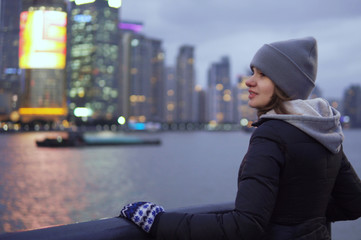 Fototapeta premium a young girl in a black jacket and hat looks at the sights of Shanghai on the waterfront of the Vaitan