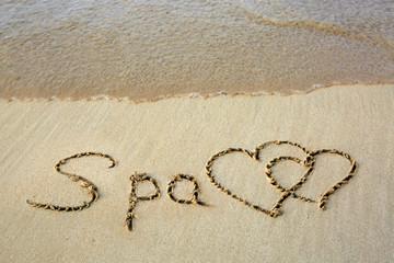 Word Spa written on the sand and two love heart.