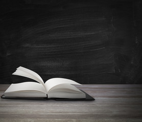 Book on table in front of blackboard