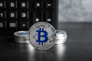 Silver bitcoins with calculator on dark table