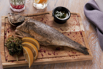 boiled sea bass, fish on a board with sauces