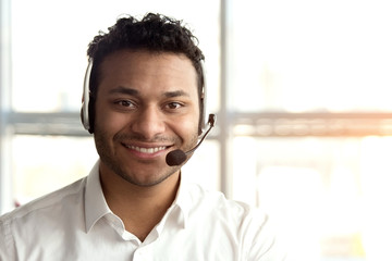 Portrait of indian operator with headset. Cheerful smiling black man face with headset in bright...