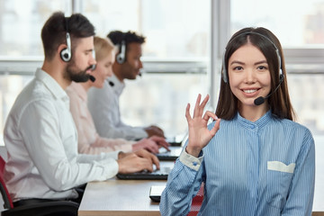 Call center operator with okay hand sign gesture. Female asian call center operator with allright...
