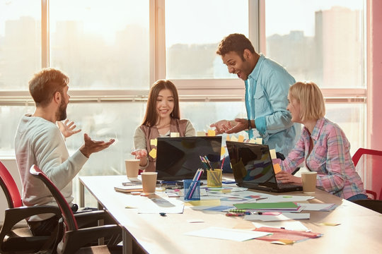 Group of creative designers brainstorming and working on a project. Designers working at messy desks in modern office. Bright windows background.