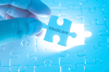 Health Care Concept. Doctor holding a jigsaw puzzle with medicare word. - obrazy, fototapety, plakaty