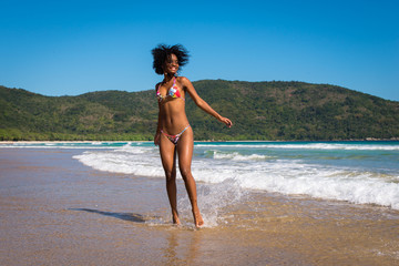 Happy and Playful Beautiful Young Woman in Bikini Playing in Waves at the Beach