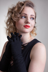 Pretty blond girl model like Marilyn Monroe in black dress with red lips on white background. 50's...