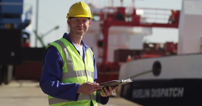 A dock worker standing at the harbor amidst shipping industry activity. Shot on RED Epic.