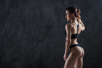 Fototapeta na wymiar Young fitness girl getting prepared for the workout isolated on dark background