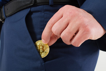 Gold Bitcoin. Businessman in suit put bit-coin into pocket. Success concept and business...