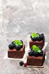 Chocolate  brownie pieces with blackberries on wooden table