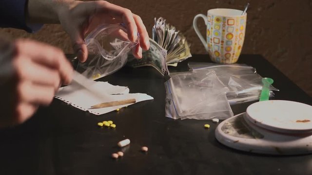 The drug dealer packs drugs - in tablets amphetamine or other - in packages and weighs them.