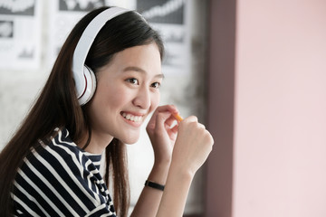 Young asian woman wearing headphones smiling with happiness while working, work at home, casual office life concept