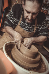elderly man making pot using pottery wheel in studio