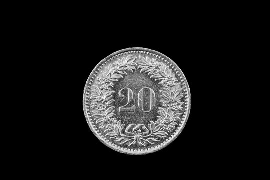 A macro image of a Swiss 20 centimes coin isolated on a black background
