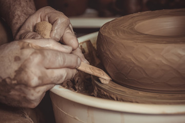 elderly man making pot using pottery wheel in studio