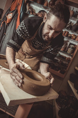 elderly man making pot using pottery wheel in studio