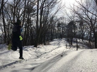 Man running on snow covered miuntain trail