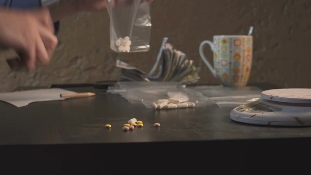 The drug dealer packs drugs - in tablets amphetamine or other - in packages and weighs them.