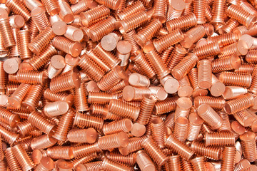 Pile of threaded copper metal screw bolts