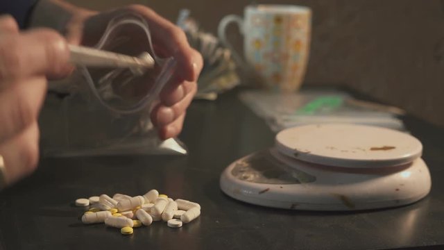 The drug dealer packs drugs - in tablets amphetamine or other - in packages and weighs them.
