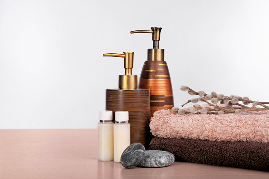Set of fresh towels and toiletries on wooden table against white background