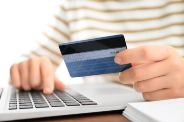 Woman with credit card and laptop at table, closeup. Internet shopping concept