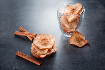 Composition with tasty apple chips and cinnamon on table