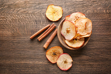 Composition with tasty apple chips and cinnamon on wooden background © Africa Studio