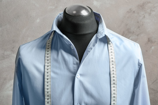 Shirt with measuring tape on tailor mannequin against light background