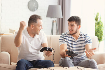Fototapeta premium Mature man playing video game with his son at home